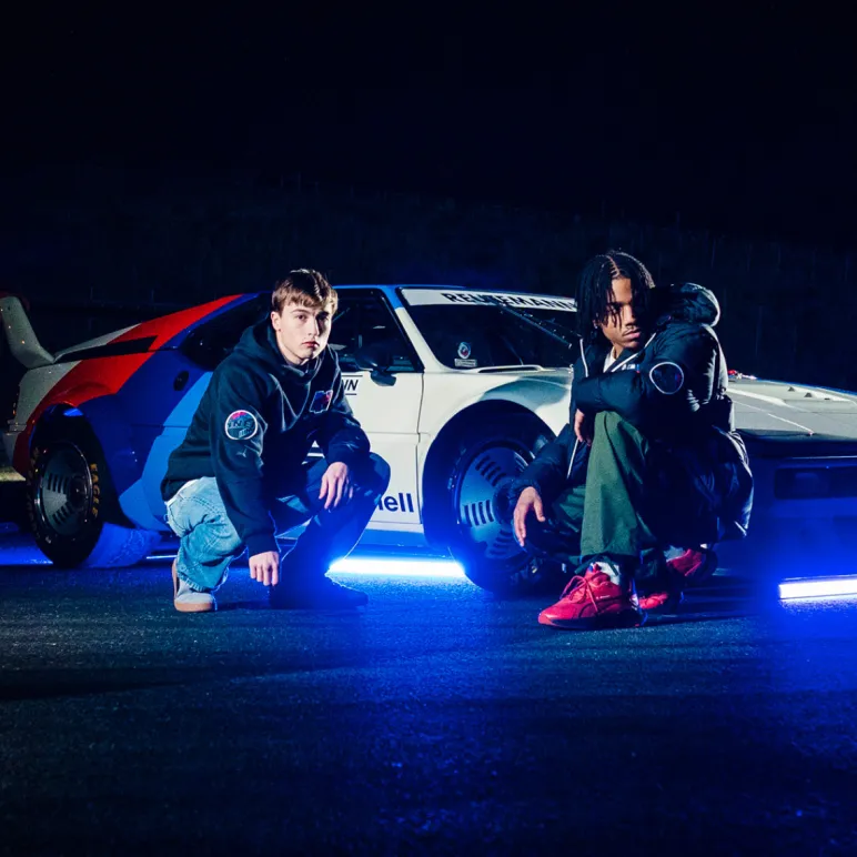 dwóch mężczyzn w ubraniach Puma Motorsport na tle samochodu